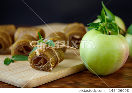 Natural dried apple fruit rolls arranged on warm wooden kitchen background 142436008