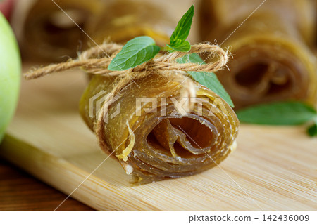 Healthy homemade apple leather rolls with green apple on rustic wooden background 142436009