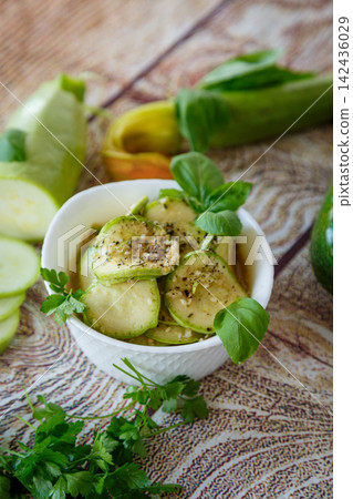 Marinated spicy zucchini with herbs on rustic wooden background Marinated spicy zucchini with herbs on rustic wooden background 142436029