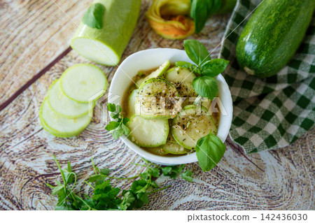 Spicy marinated zucchini with basil on rustic wood background Spicy marinated zucchini with basil on rustic wood background 142436030