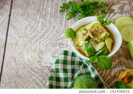 Seasoned zucchini slices with basil on rustic wooden background Seasoned zucchini slices with basil on rustic wooden background 142436031