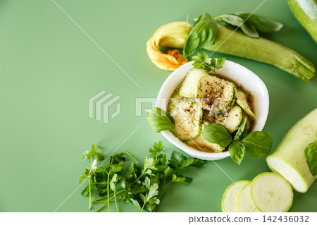 Spicy marinated zucchini with garlic and spices on green background Spicy marinated zucchini with garlic and spices on green background 142436032
