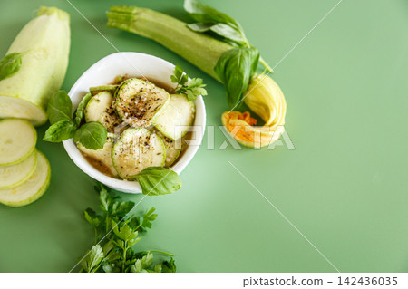 Marinated zucchini slices with seasoning served on green background Marinated zucchini slices with seasoning served on green background 142436035