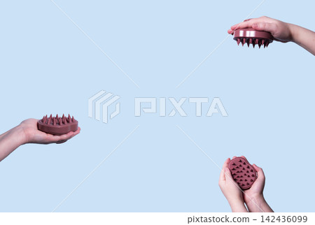 Hair pink scalp massager in woman hand on the pink background isolated. Image with copy space. Mock up for design and banner 142436099