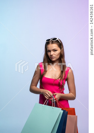 Young woman holding multiple paper shopping bags, reflecting retail therapy, fashion trends, consumption, and a modern lifestyle Young woman holding multiple paper shopping bags, reflecting retail therapy, fashion trends, consumption, and a modern lifestyle 142436161