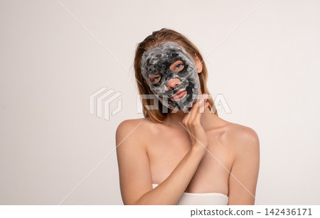 Woman applying detoxifying bubble sheet mask for healthy skin, receiving a facial treatment Woman applying detoxifying bubble sheet mask for healthy skin, receiving a facial treatment 142436171