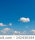 Serene sky view with soft cumulus clouds and vibrant blue background 142436344