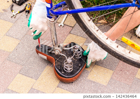 Man flipping bike upside down before house. Checking wheels and chain for damage. Bike repair shows self reliance. Seasonal preparation for summer rides Man flipping bike upside down before house. Checking wheels and chain for damage. Bike repair shows self reliance. Seasonal preparation for summer rides 142436464