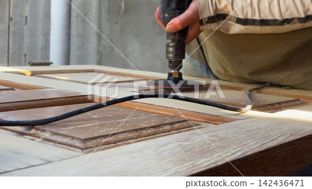 Male hands use electric polishing machine to smooth and refine wooden door surface. The rotating pad carefully treats wood, enhancing texture and finish during detailed restoration or renovation work Male hands use electric polishing machine to smooth and refine wooden door surface. The rotating pad carefully treats wood, enhancing texture and finish during detailed restoration or renovation work 142436471