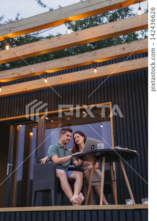 Couple using laptop spending time together on patio. Couple using laptop spending time together on patio. 142436626