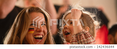 Excited football fans, mother with little daughter, supproting German national team in live soccer match at stadium. Excited football fans, mother with little daughter, supproting German national team in live soccer match at stadium. 142436844