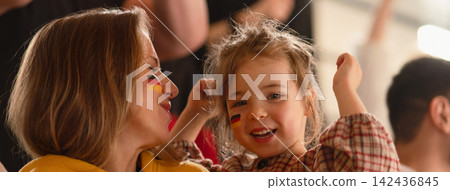 Excited football fans, mother with little daughter, supproting German national team in live soccer match at stadium. Excited football fans, mother with little daughter, supproting German national team in live soccer match at stadium. 142436845