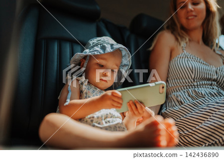 Toddler using smartphone during family road trip. Toddler using smartphone during family road trip. 142436890