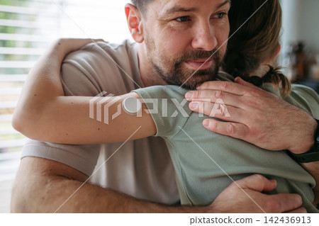 Dad hugging with daughter with diabetes in kitchen at home. Dad hugging with daughter with diabetes in kitchen at home. 142436913