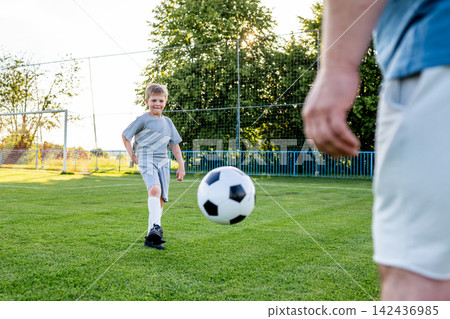 Dad helping young boy improve football technique during training. Dad helping young boy improve football technique during training. 142436985