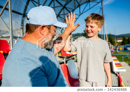 Father and son cheering for football team during match at stadium. Father and son cheering for football team during match at stadium. 142436986