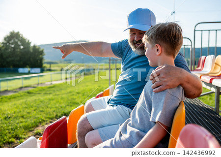 Father and son cheering for football team during match at stadium. 142436992