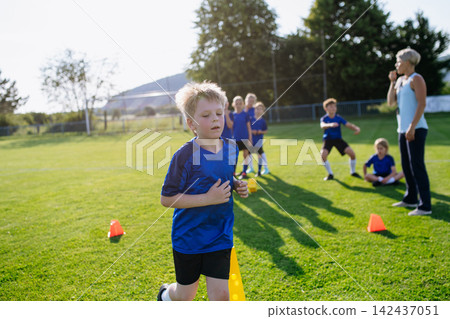 Children practicing speed and coordination drills during football training. Children practicing speed and coordination drills during football training. 142437051