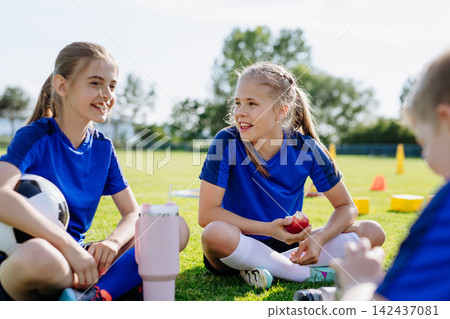 Children relaxing together after youth football training and exercise. Children relaxing together after youth football training and exercise. 142437081