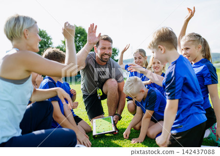 Youth soccer team listening to game strategy during practice. Youth soccer team listening to game strategy during practice. 142437088