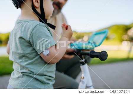 Boy with continuous glucose monitor eating snack to treat low blood sugar. Boy with continuous glucose monitor eating snack to treat low blood sugar. 142437104
