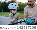 Little boy having snack while riding bike in park. 142437106