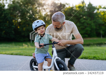 Father and son enjoying bike riding in park. Father and son enjoying bike riding in park. 142437119