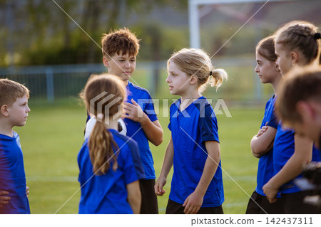 Young football players talking during training session on pitch. Young football players talking during training session on pitch. 142437311