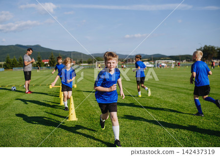 Young soccer players running aroung training cones during football practice Young soccer players running aroung training cones during football practice 142437319