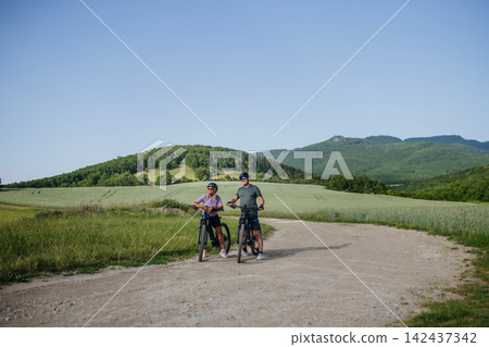 Active senior couple exploring nature on electric bicycles Active senior couple exploring nature on electric bicycles 142437342