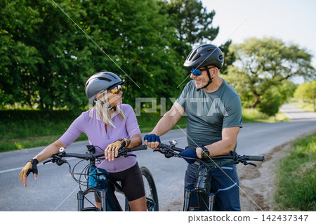 Active senior couple preparing for electric bike trip. Active senior couple preparing for electric bike trip. 142437347