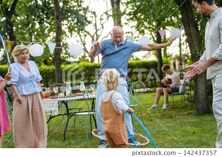 Family enjoying outdoor summer gathering with playful activities. Family enjoying outdoor summer gathering with playful activities. 142437357