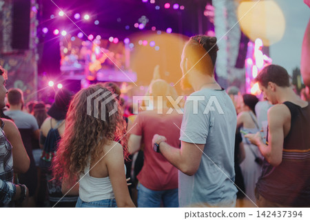 Rear view of group of young friends dancing at summer festival. Rear view of group of young friends dancing at summer festival. 142437394