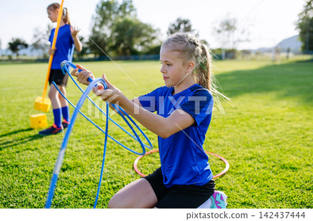 Children helping prepare football training session on sports field. Children helping prepare football training session on sports field. 142437444