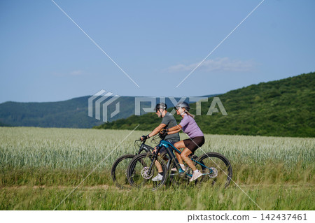 Side view of senior couple exploring nature on electric bicycles Side view of senior couple exploring nature on electric bicycles 142437461