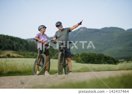 Active senior couple exploring nature on electric bicycles Active senior couple exploring nature on electric bicycles 142437464