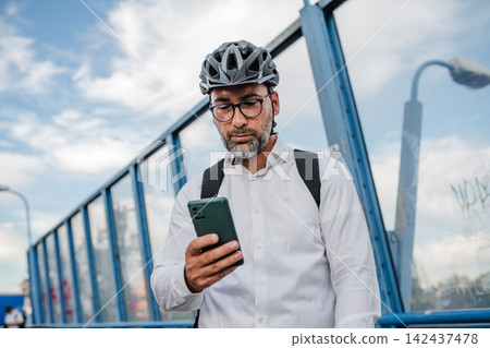 Manager on bike, reading text message on phone. Manager on bike, reading text message on phone. 142437478