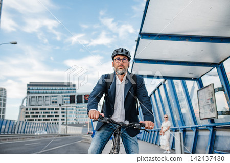 City commuter riding bike to office, wearing backpack and helmet. 142437480