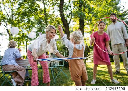 Family enjoying outdoor summer gathering with playful activities. Family enjoying outdoor summer gathering with playful activities. 142437506