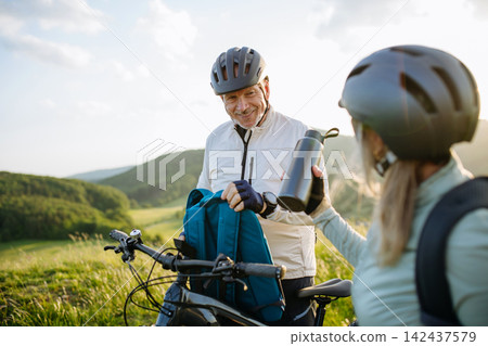 Senior couple planning cycling route with smartphone during e-bike trip. Senior couple planning cycling route with smartphone during e-bike trip. 142437579
