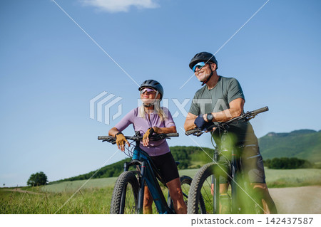 Senior couple taking break during e-bike ride through countryside Senior couple taking break during e-bike ride through countryside 142437587