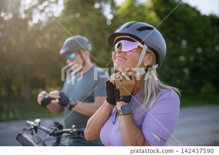 Active senior couple preparing for electric bike trip. Active senior couple preparing for electric bike trip. 142437590