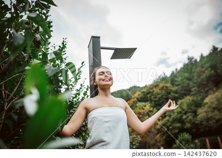 Beautiful woman resting in garden after using home sauna. Woman taking care of her body and mind, wellness routine. Beautiful woman resting in garden after using home sauna. Woman taking care of her body and mind, wellness routine. 142437620