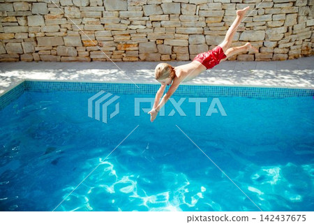 Boy having fun at outdoor swimming pool on family holiday. Boy having fun at outdoor swimming pool on family holiday. 142437675