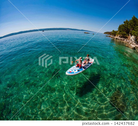Brother and sister paddleboarding during family summer vacation in Croatia. Brother and sister paddleboarding during family summer vacation in Croatia. 142437682