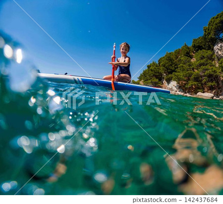 Young girl paddleboarding during family summer vacation in Croatia. 142437684