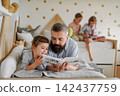 Dad reading with his daughter during home learning time. 142437759