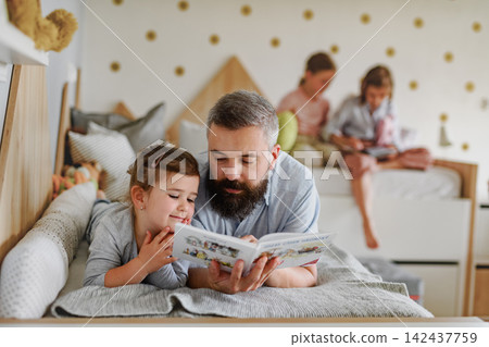 Dad reading with his daughter during home learning time. Dad reading with his daughter during home learning time. 142437759