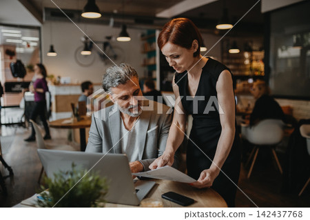 Man and woman having business meeting in a coffee shop. Man and woman having business meeting in a coffee shop. 142437768