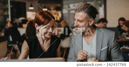 Man and woman having business meeting in a coffee shop. Man and woman having business meeting in a coffee shop. 142437769